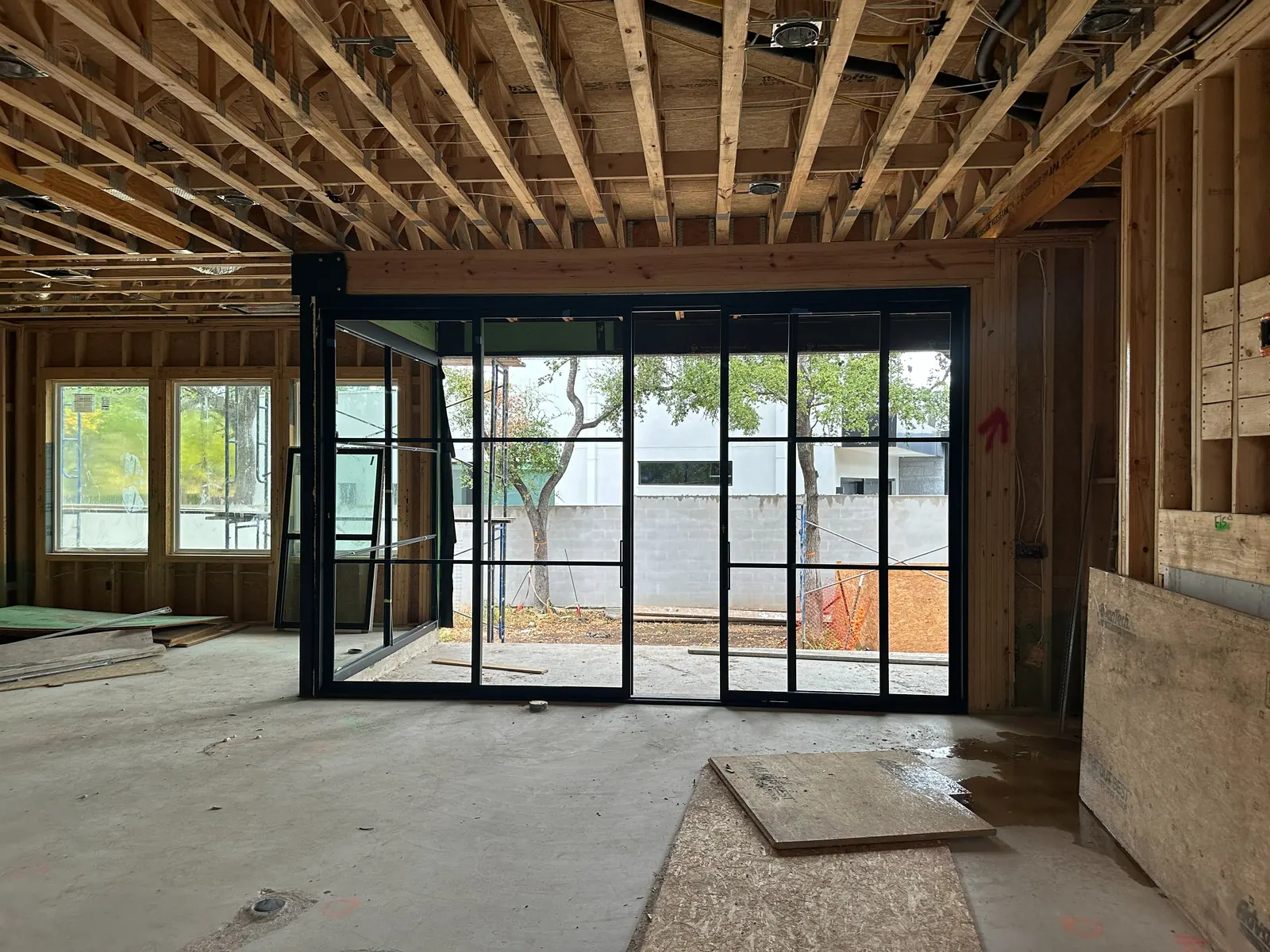 Framed interior space with large glass doors during construction
